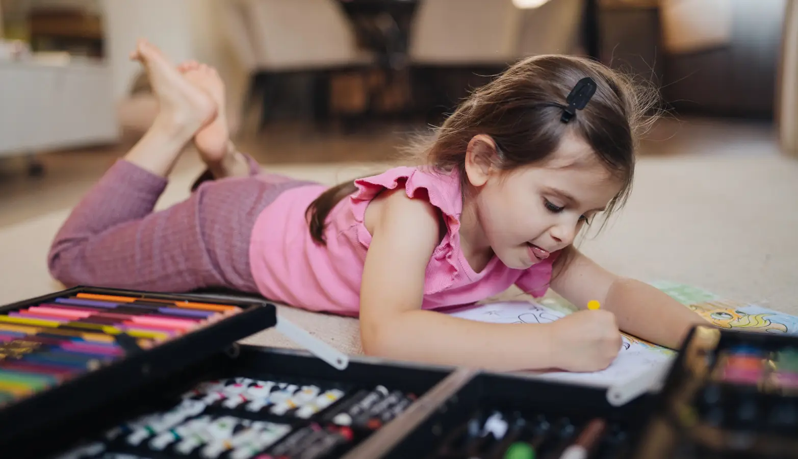 A 4-year-old child sitting at a table drawing with crayons, engaged in a screen-free activity